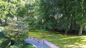 Un parc avec un sentier dallé, de l’herbe verte et des arbres.