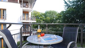 Une table ronde avec deux chaises sur un balcon, une bouteille de jus d’orange et une brochure.