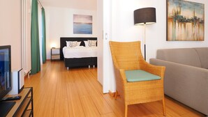 Une chambre d’hôtel moderne comprenant un lit, une chaise, un canapé, un tableau et une lampe.
