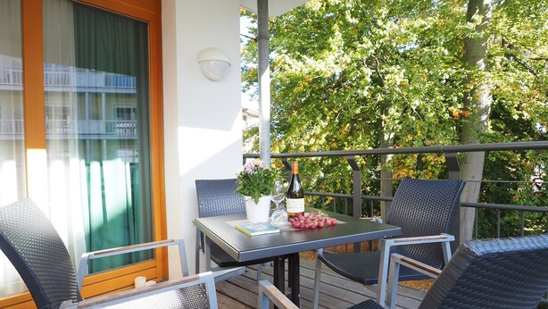 Ein Balkon mit Tisch, Stühlen und einer Weinflasche.