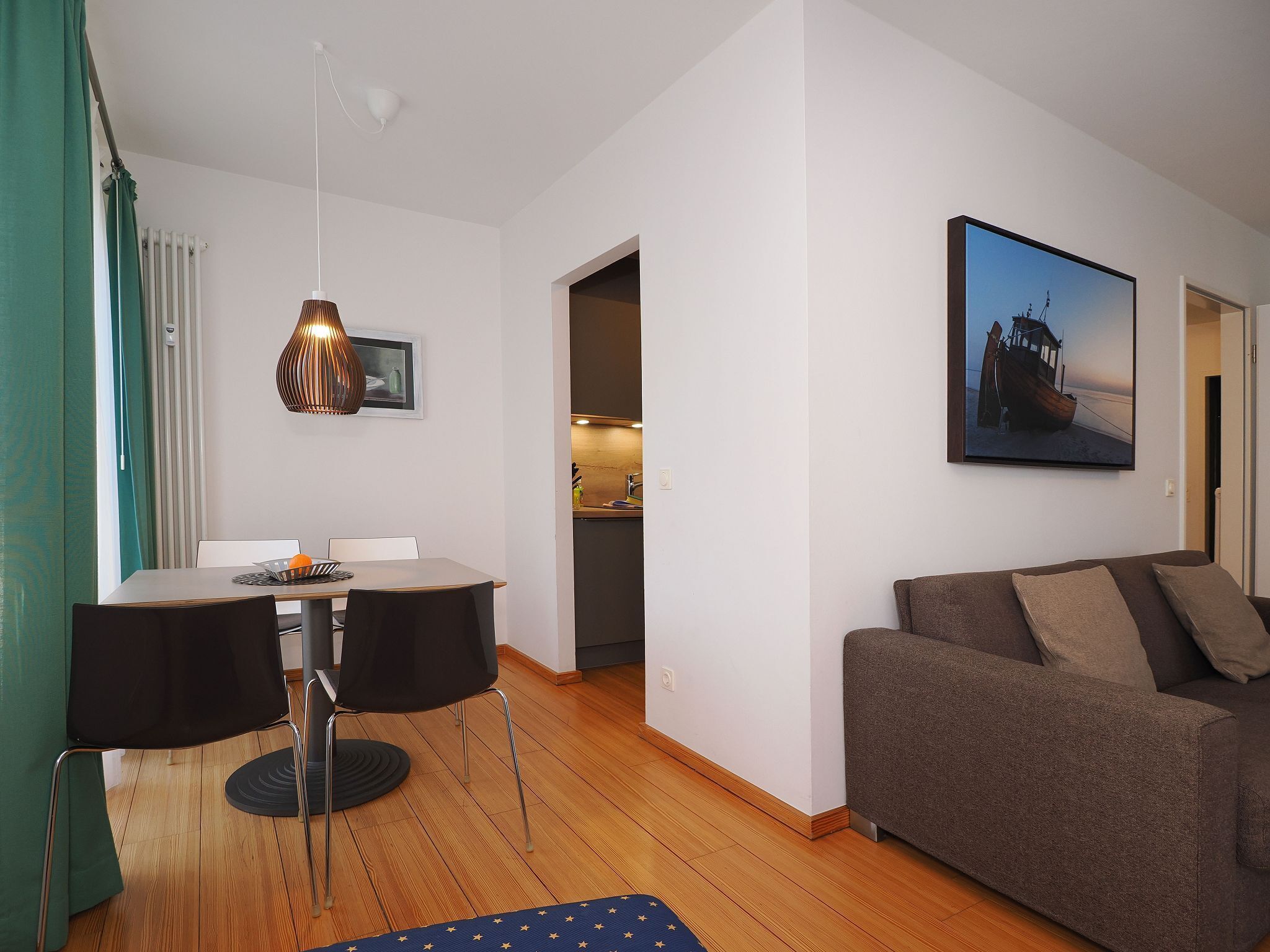 A modern living room with a dining area, a sofa, and a kitchen in the background.