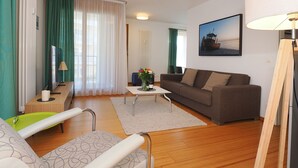 Ein modernes Wohnzimmer mit einer Couch, einem Couchtisch, einem Fernseher und einem Bild an der Wand.
