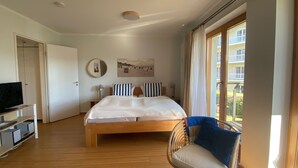 Une chambre à coucher avec un lit, une chaise, une télévision et une fenêtre.