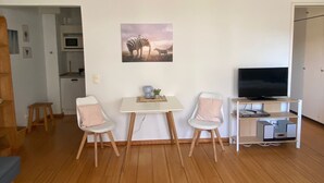 Un salon comprenant un coin repas, un téléviseur et un tableau accroché au mur.