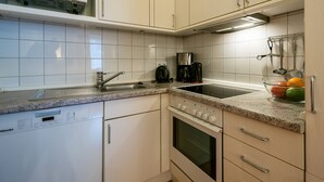 Une cuisine avec des meubles blancs, un four à micro-ondes, une machine à café et un lave-vaisselle.