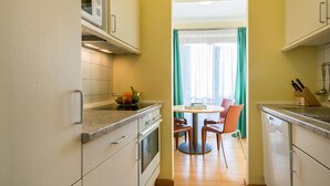 Una cucina angusta con zona pranzo, un forno a microonde e una ciotola di frutta.