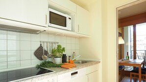 Uma cozinha moderna com armários brancos, micro-ondas, pia e área de jantar com mesa e cadeiras.