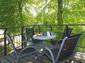 A terrace with metal chairs and a table, surrounded by a metal railing, overlooking a forested area. - 1-bedroom apartment with a balcony (Seebad Heringsdorf)