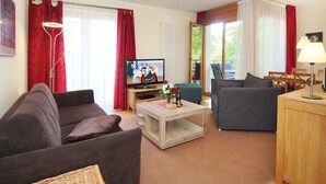 Uma sala de estar com sofá, mesa de centro, televisão e um espaço de jantar com cadeiras e mesa.