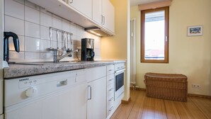 A modern kitchen with white cabinets, a built-in dishwasher, and a coffee maker.