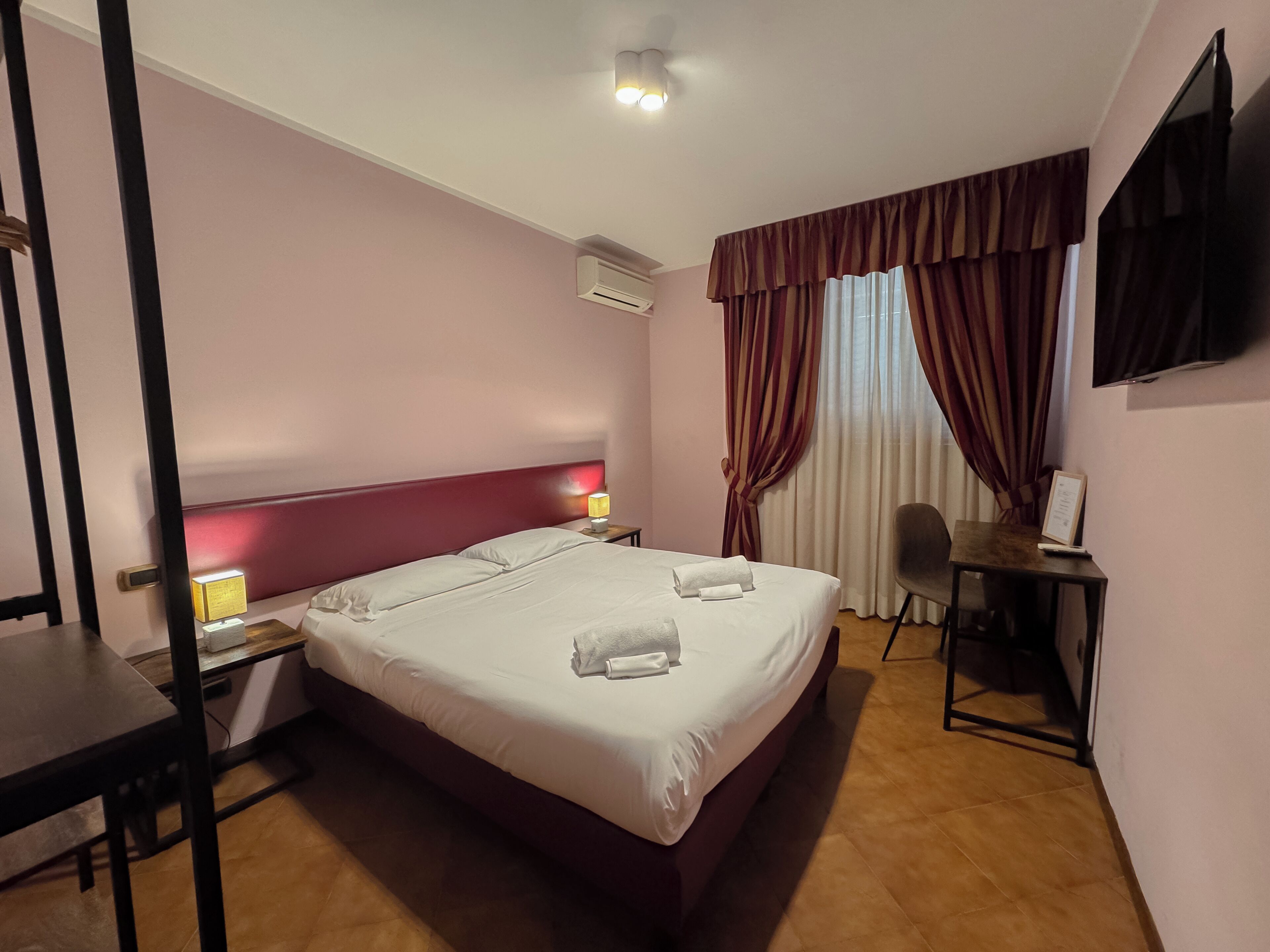 Une chambre d’hôtel avec un grand lit, un bureau, une chaise et un téléviseur à écran plat.
