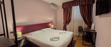 Une chambre d’hôtel avec un grand lit, un bureau, une chaise et un téléviseur à écran plat.