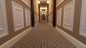 A hallway with patterned carpet, white wainscoting, and a series of doors. - Hotel Santa Maura (Rome)