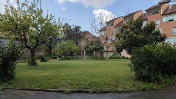 A residential area with a grassy lawn, trees, and brick apartment buildings.