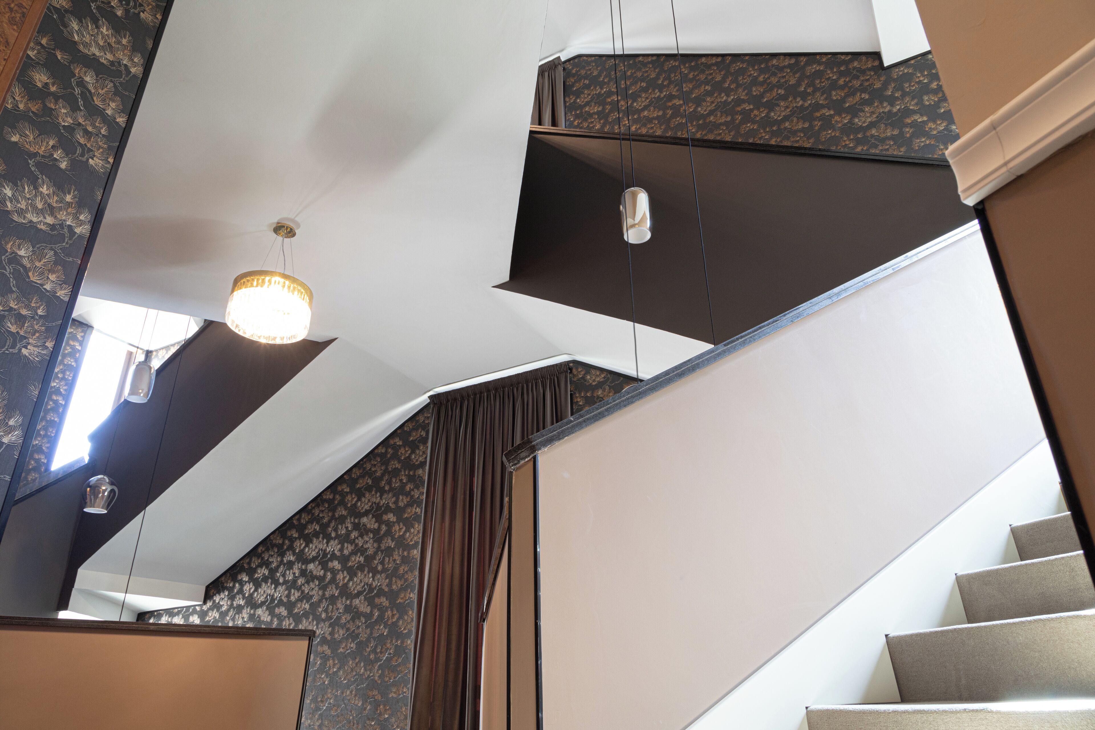 Eine Treppe mit modernem Design, einer Chandelieber und Wandtapete mit Muster.