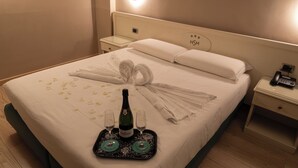 A hotel room with a neatly made bed, a bottle of champagne, and two glasses on a tray. - Hotel Santa Maura (Rome)
