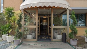The entrance of Hotel Santa Mauria with a glass door, a white awning, and a doormat with the hotel's name. - Hotel Santa Maura (Rome)