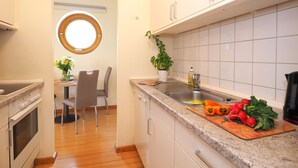 Uma cozinha com pia, bancada e área de refeições com uma cadeira e mesa.