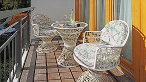 A balcony with wicker furniture, including two chairs and a small table, and a bottle of water. - 1-raum-appartement mit Balkon (Seebad Heringsdorf)
