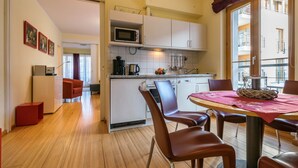 A compact kitchen with white cabinets, a microwave, and a coffee maker. There is a dining area with a table and chairs. - Appartement mit 1 Schlafzimmer und Balkon (Seebad Heringsdorf)