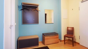 Ein Zimmer mit Schrank, einer Bank, einem Stuhl und einem Spiegel an der Wand.