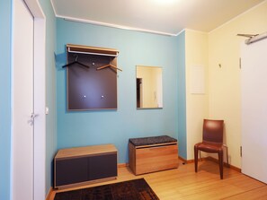 Une pièce comprenant une armoire, un banc, une chaise et un miroir au mur.