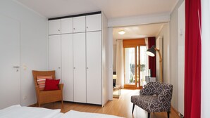 A bedroom with a bed, a wardrobe, a chair, and a view of an outdoor area through a door. - Apartment with 1 bedroom and terrace (Seebad Heringsdorf)