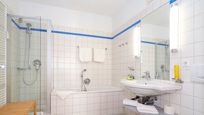 A modern bathroom with a glass-enclosed shower, a freestanding bathtub, and a sink with a mirror. - Apartment with 1 bedroom and terrace (Seebad Heringsdorf)