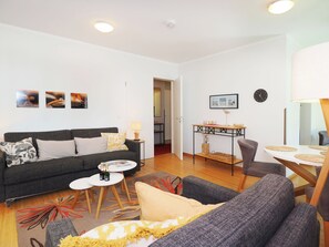 Een moderne woonkamer met een bank, salontafel en een eethoek met een tafel en stoelen.