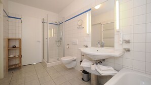 A modern bathroom with a glass-enclosed shower, a toilet, a sink, and a bathtub. - Apartment with 2 bedrooms and balcony (Seebad Heringsdorf)