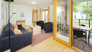 A modern living room with a sofa, chairs, a table, and a balcony with a view. - Apartment with 2 bedrooms and balcony (Seebad Heringsdorf)