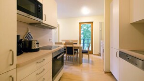 A modern kitchen with a microwave, stove, and dishwasher. There is a dining area with a table and chairs. - Apartment with 2 bedrooms and balcony (Seebad Heringsdorf)