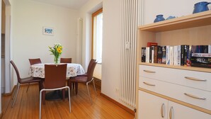 En spiseplads med et bord dækket til fire personer, en radiator og en bogreol med bøger.