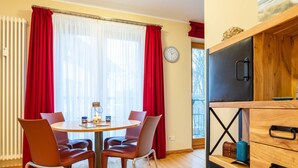 Un coin repas avec une table ronde, des rideaux rouges et une horloge au mur.