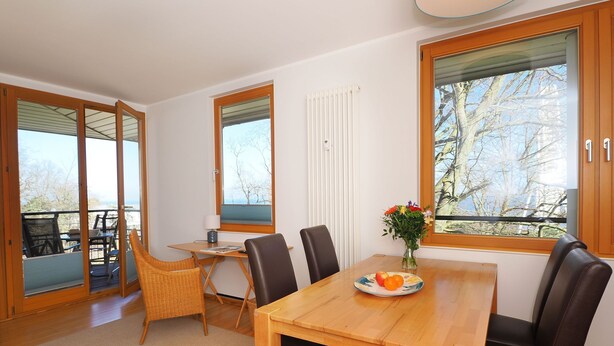 A dining area with a wooden table, black chairs, a wicker chair, and a vase with flowers. - Apartment with 1 bedroom and balcony (Seebad Heringsdorf)