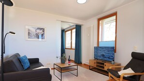 A modern living room with a black sofa, a wooden coffee table, a TV, and a chair. - Apartment with 1 bedroom and balcony (Seebad Heringsdorf)
