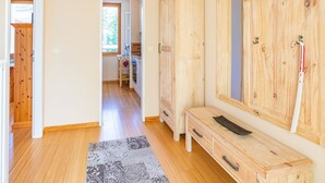 Um corredor com piso de madeira, um banco, um espelho com moldura de madeira e um guarda-roupa de madeira.