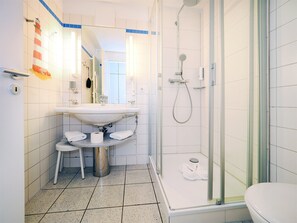 Een moderne badkamer met een douchecabine van glas, een wastafel met een handdoekhouder en een toilet.