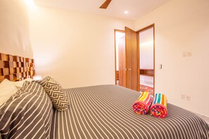 A bedroom with a bed, striped bedding, a wooden headboard, and a door leading to another room.