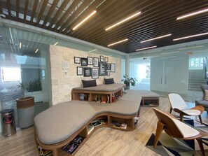 A modern lounge area with curved seating, a bookshelf, and motivational wall art.