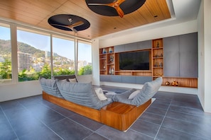 A modern living room with a built-in sofa, a flat-screen TV, and a ceiling fan.