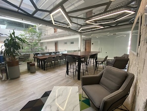 A modern office space with a long conference table, several chairs, a sofa, and a potted plant.