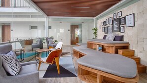 A modern interior with a wooden ceiling, a glass wall, and a seating area with a sofa and chairs.