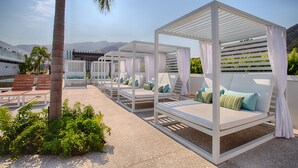 A resort with outdoor seating areas, including white canopies and lounge chairs with cushions.