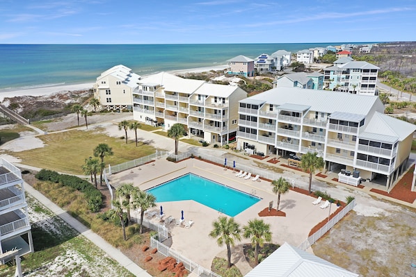 A beachfront hotel with multiple balconies, a swimming pool, and a beach view.
