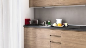 Cocina moderna con armarios de madera, pileta de acero inoxidable y encimera negra.