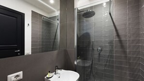 Un baño moderno con ducha, lavamanos y espejo.