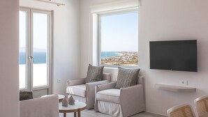 Uma sala de estar moderna com varanda, televisão de tela plana e vista para o mar.