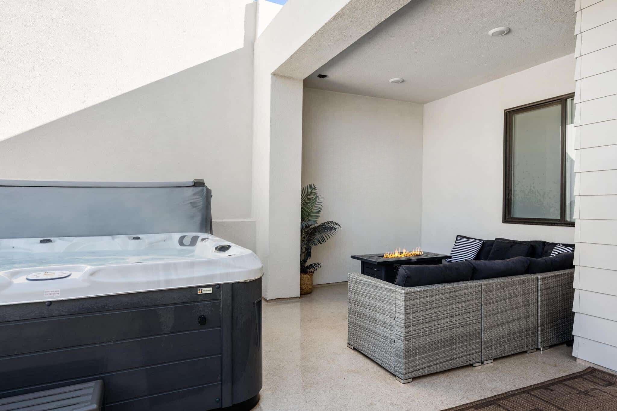 A patio area with a hot tub, wicker furniture, and a potted plant.