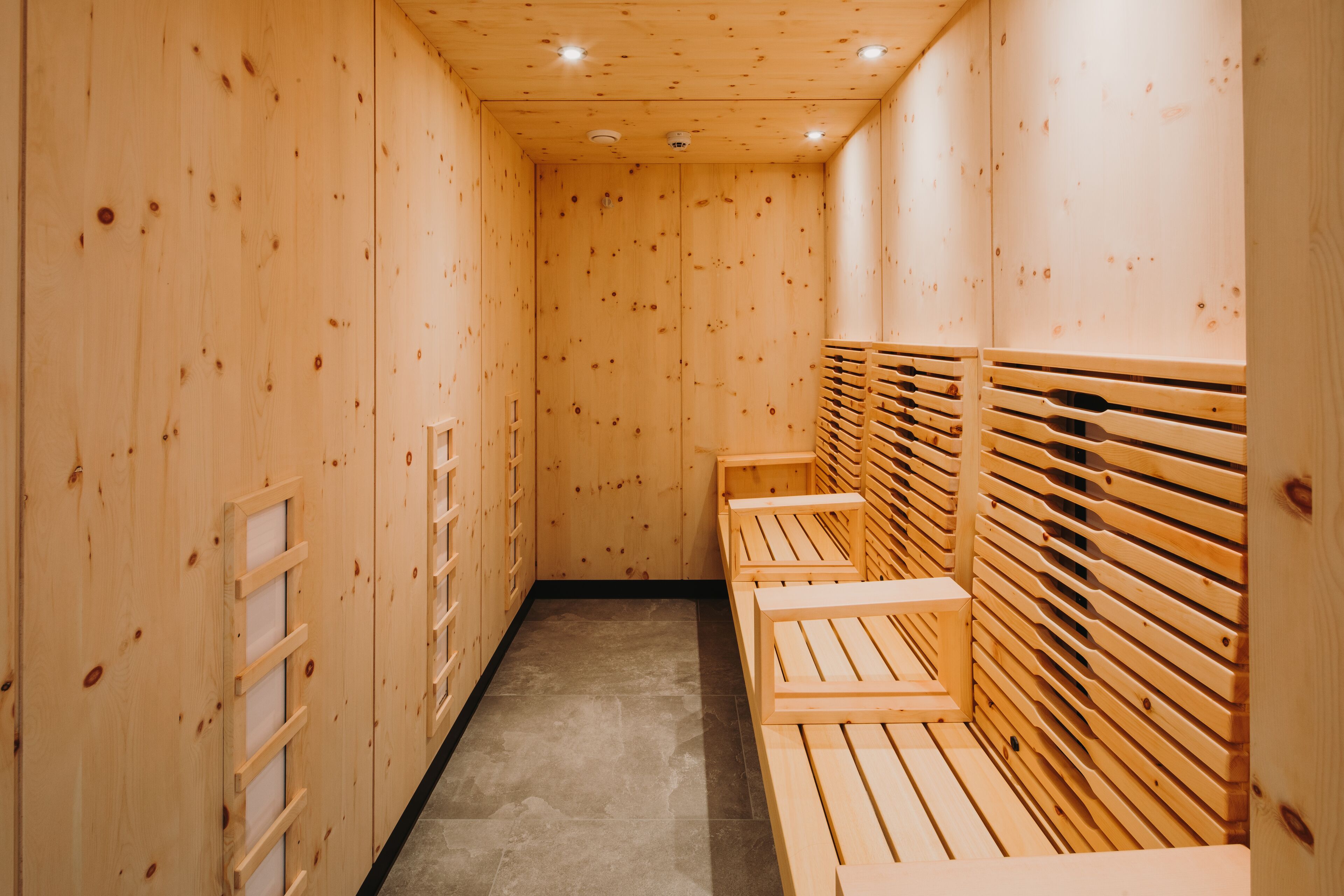 Eine Holzsauna mit Bänken und einer Lamellenwand.